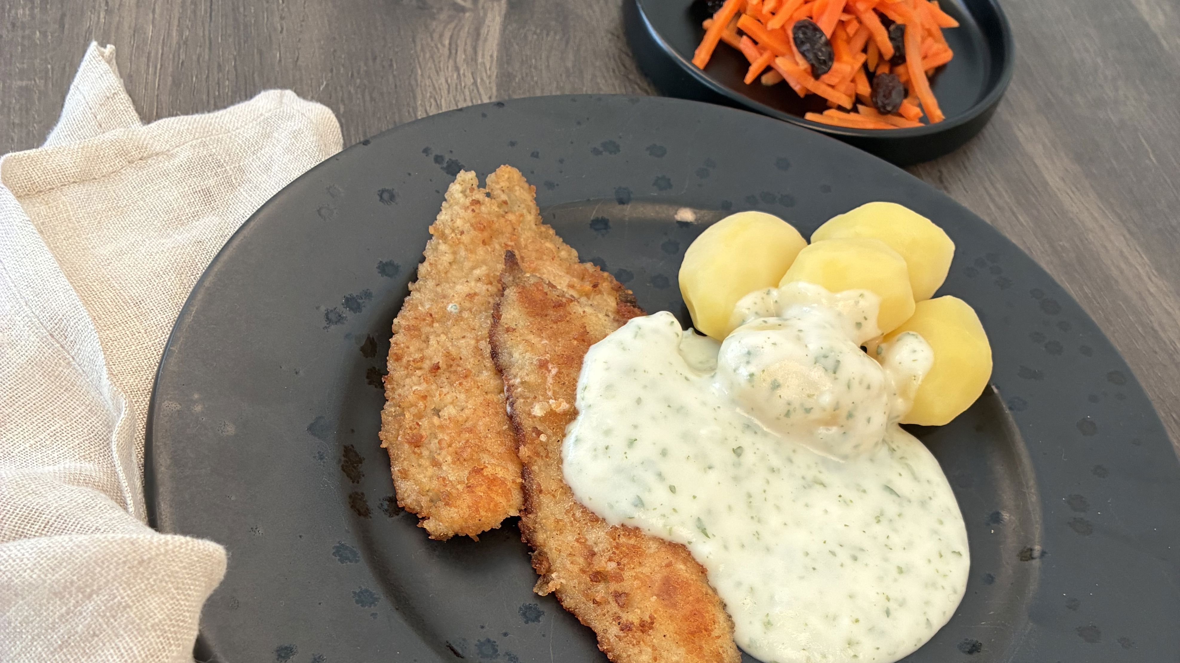 Tallerken med paneret kød, sovs, kartofler og salat