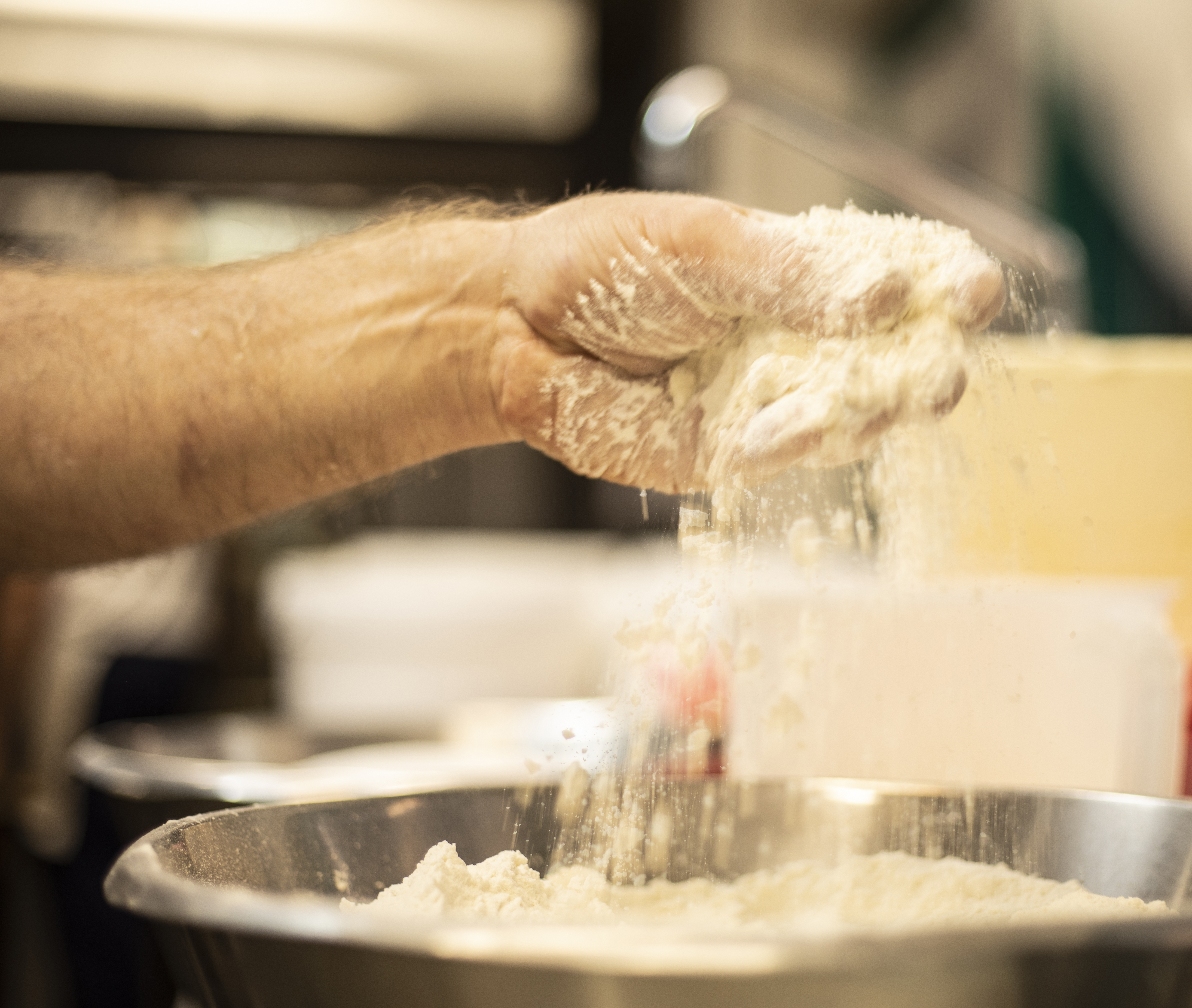 Hånd tilsætter mel i skål