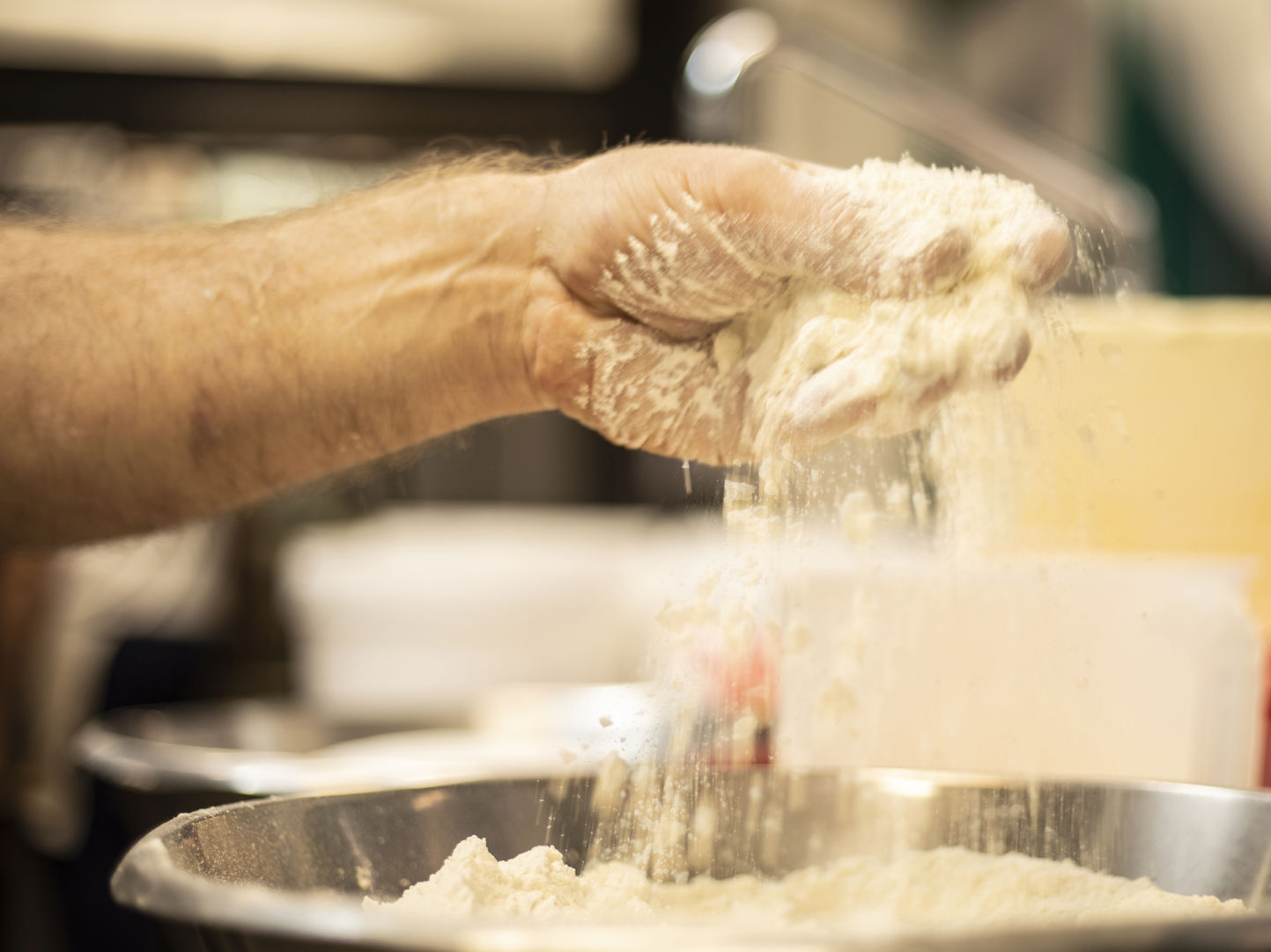 Hånd tilsætter mel i skål